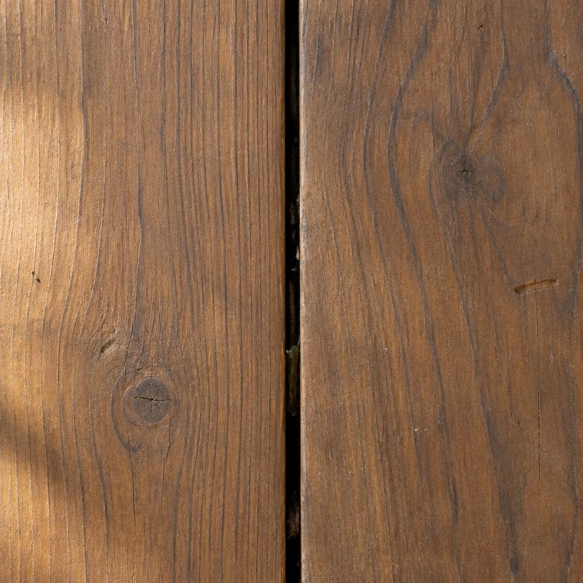 Close-up van twee warmbruine hardhouten vlonderplanken met de kier ertussen